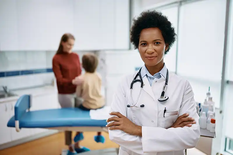 doctor smiling with young physical exam patient in background