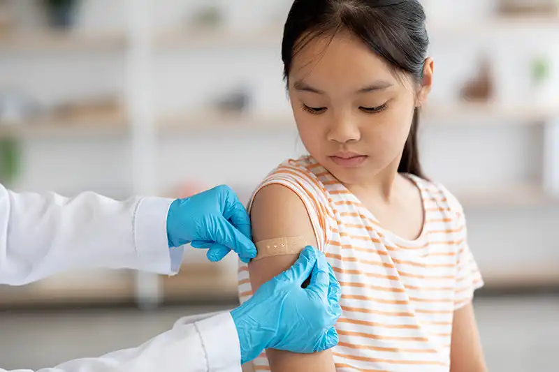 nurse putting band aid on childs arm after tetanus shot